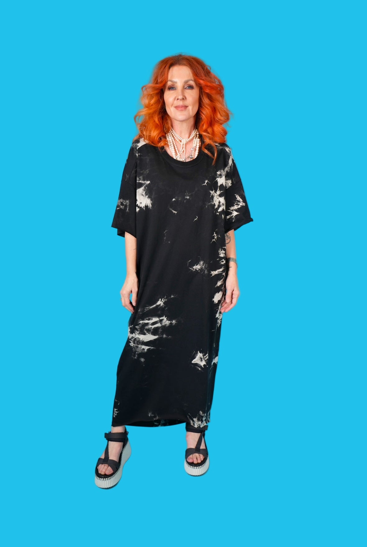 Woman wearing a black dress with white patterns on a blue background